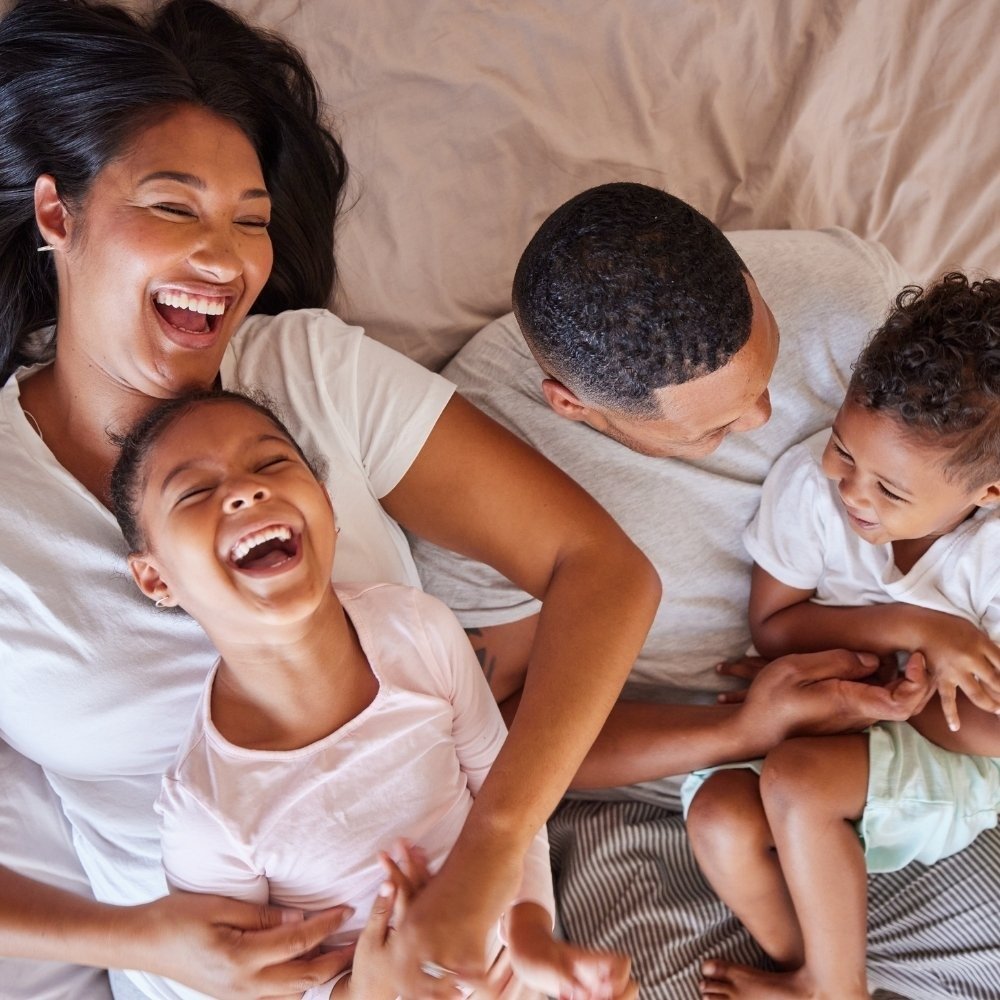playful family members cuddle and wrestle in bed
