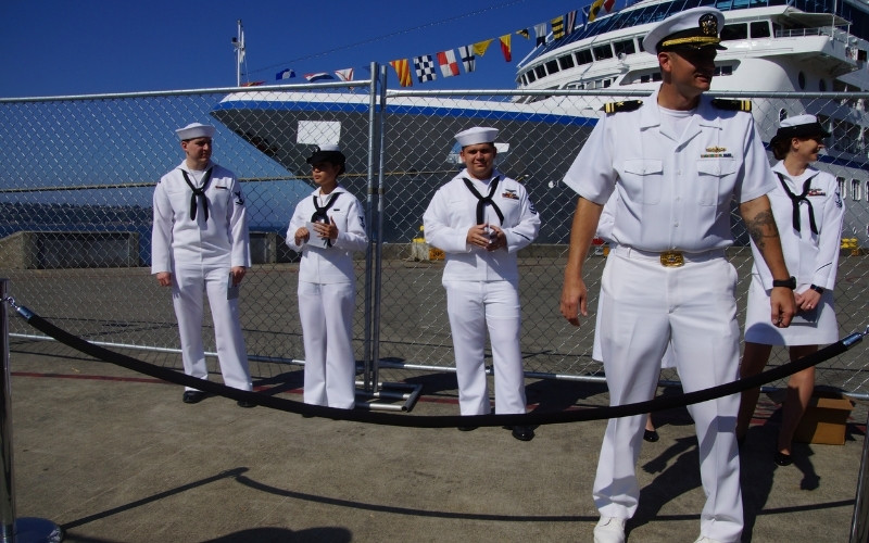 sailors stand outside a ship in port
